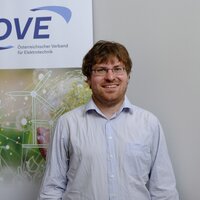 Ein Mann steht vor einem Banner des Österreichischen Verbands für Elektrotechnik.
