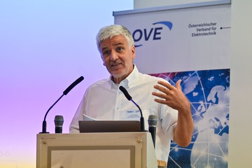 Mann spricht an einem Podium, präsentiert beim OVE-Verband für Elektrotechnik.