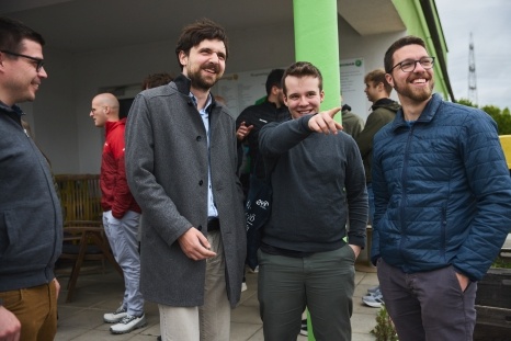 Vier Männer unterhalten sich freundschaftlich im Freien und lachen gemeinsam.
