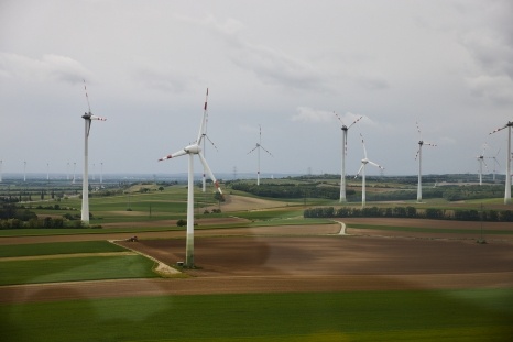 Windräder stehen auf einem weitläufigen Feld unter bewölktem Himmel.