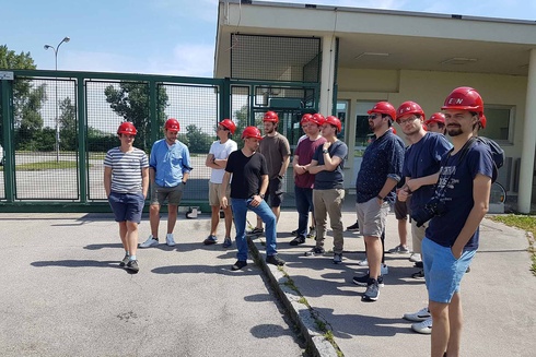 Eine Gruppe von Männern mit roten Helmen steht vor einem Tor.