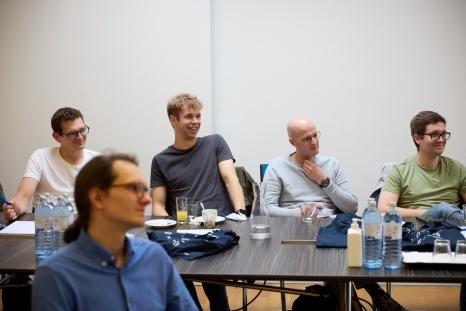 Eine Gruppe junger Männer hört aufmerksam in einem Seminarraum zu.