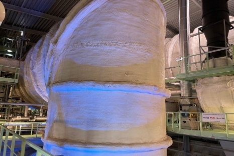 Industrielle Rohrleitungssysteme in einem verarbeiteten Raum mit blauem Licht.