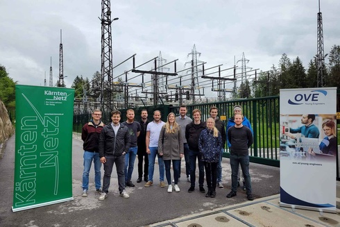 Gruppe von Menschen vor Stromanlagen mit Bannern von Kärnten Netz und OVE.