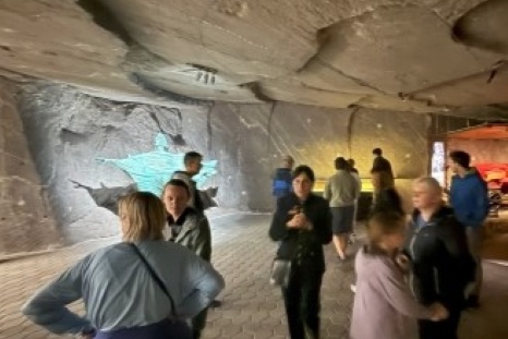 Besucher stehen in einer Höhle mit leuchtendem Wandbild und betrachten die Umgebung.