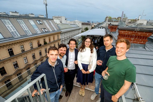 Gruppe von sechs Personen auf einer Dachterrasse mit Getränken.