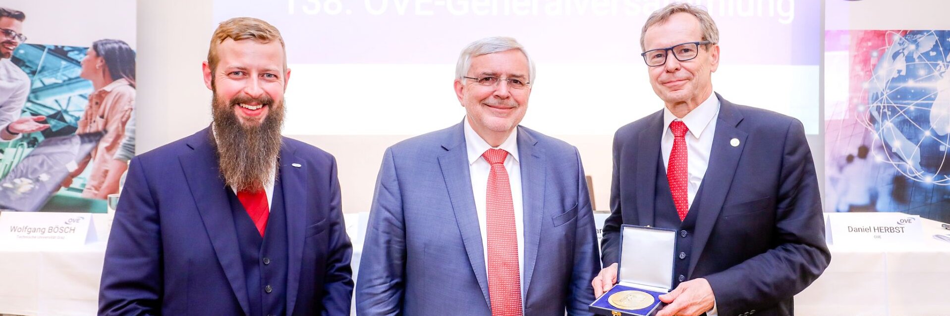 Drei Männer stehen lächelnd zusammen bei der 138. OVE-Generalversammlung.