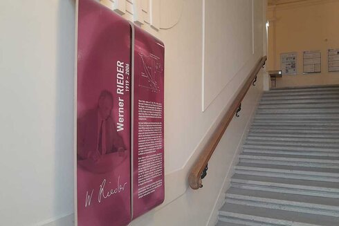 Informationstafel über Werner Rieder an einer Treppe.