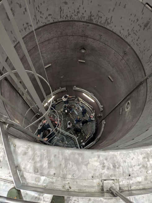 Blick nach unten in einen großen, runden Schacht mit niedrigen Geländern.