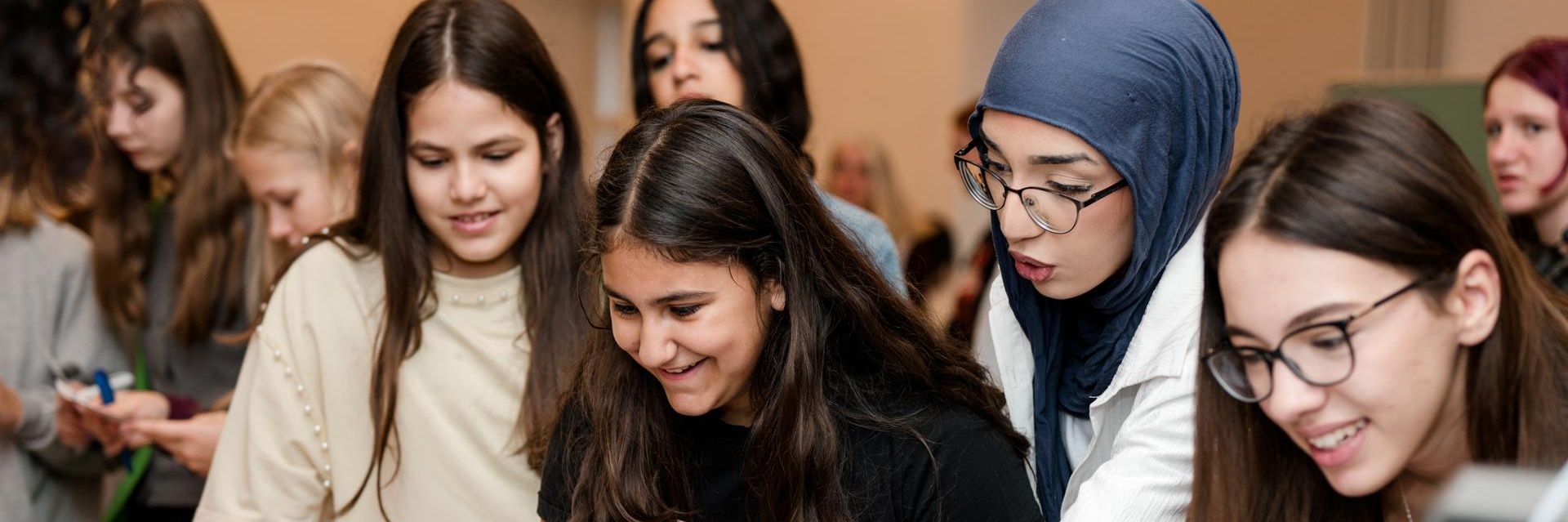 Gruppe junger Frauen, die gemeinsam an Laptops arbeiten und diskutieren.