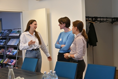 Drei Frauen unterhalten sich in einem Konferenzraum.