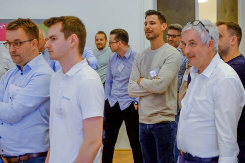 Gruppierung von Männern, die an einer Veranstaltung teilnehmen und miteinander sprechen.