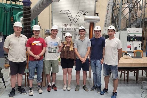 Gruppe von sieben Personen in Sicherheitshelmen in einer technischen Umgebung.
