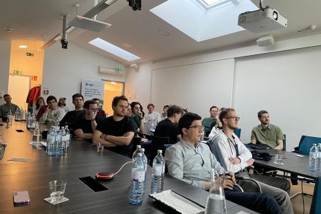 Gruppe von Menschen sitzt in einem Konferenzraum und hört aufmerksam zu.