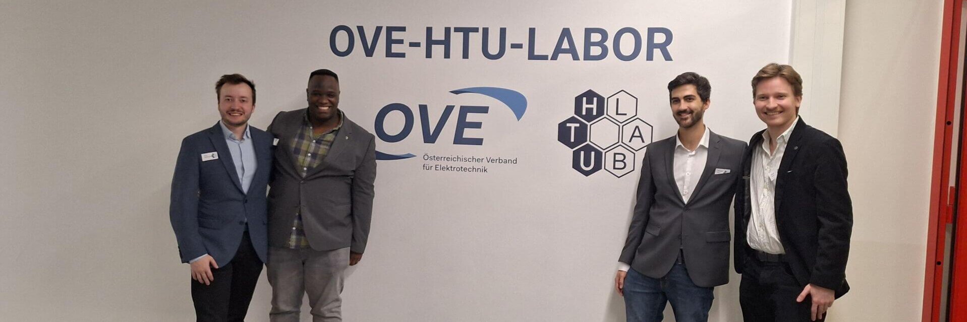 Vier Personen posieren vor dem OVE-HTU-Labor-Schild.