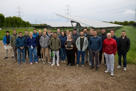 Gruppennfoto von Menschen vor Solaranlagen auf einem Feld.