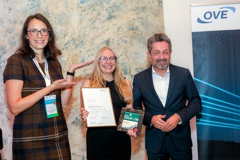 Ausgezeichnete Preisträgerin, flankiert von einer Frau und einem Mann