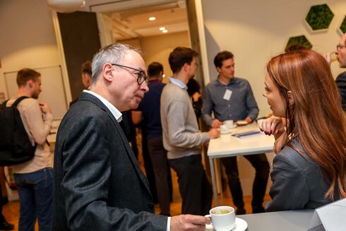 Zwei Personen unterhalten sich bei einer Networking-Veranstaltung mit Kaffeetassen.