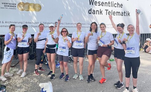 Gruppierung von Menschen in Sportkleidung, die ihre Medaillen nach einem Lauf feiern.