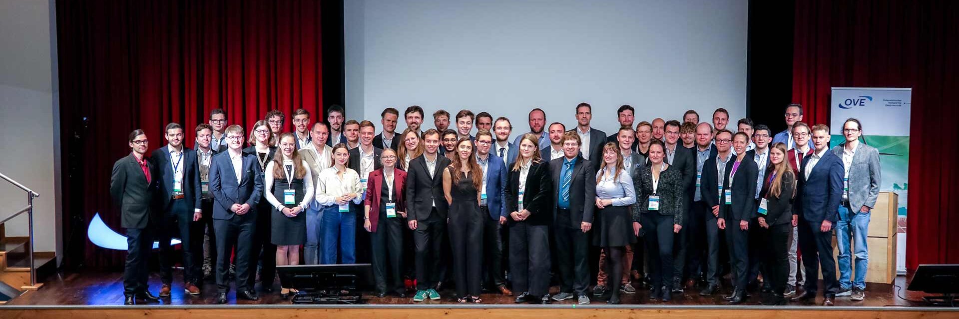 Gruppenfoto von Teilnehmern einer Konferenz auf einer Bühne.
