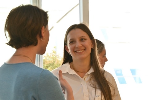 Zwei Frauen unterhalten sich lachend bei einer informellen Veranstaltung.
