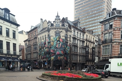 Bunte Wandmalerei mit Pflanzenmotiven an einem historischen Gebäude in der Stadt.