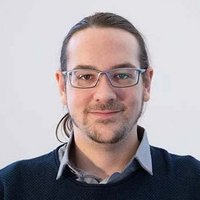 Porträt eines Mannes mit Brille und lächelndem Gesicht.
