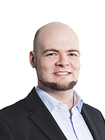 Porträt eines lächelnden Mannes in Anzug mit kurzem Haarschnitt.