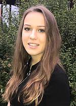 Porträt einer jungen Frau mit langen, glatten Haaren vor grünem Hintergrund.