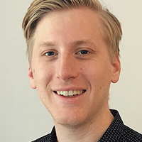 Porträt eines lächelnden jungen Mannes mit blonden Haaren.