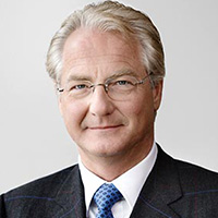 Portrait eines Mannes mit Brille, blonden Haaren und Anzug.